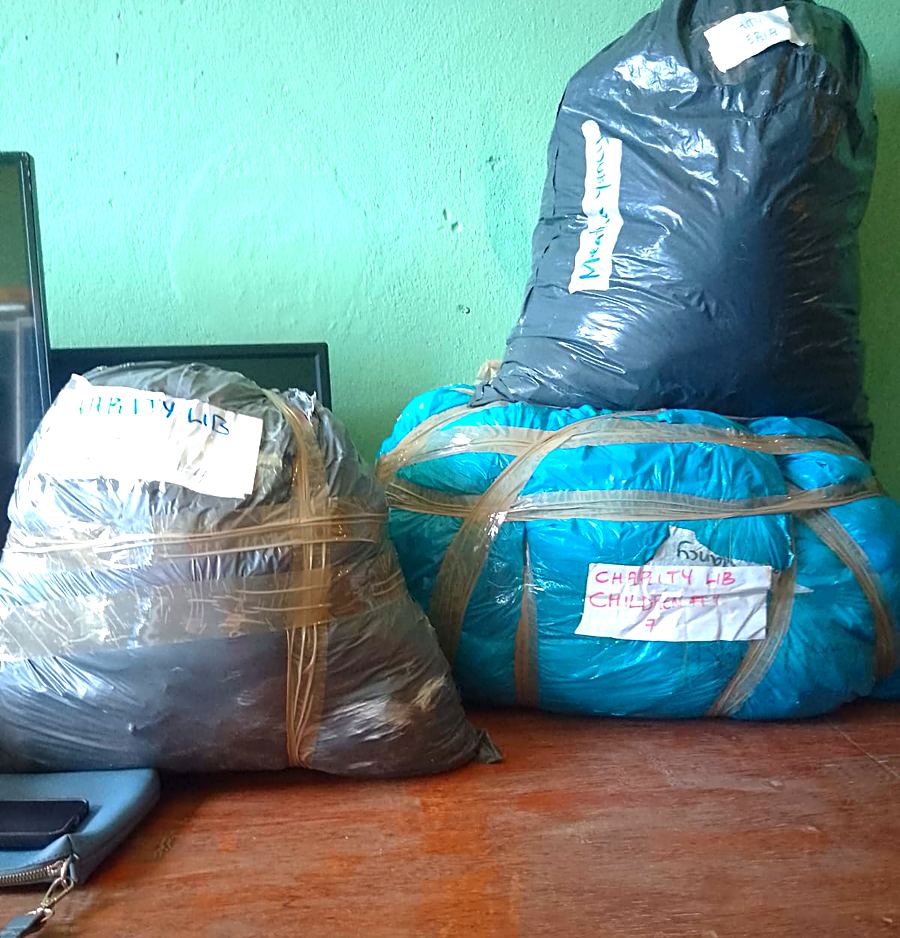 Donation bundles hand-labeled 'Charity Lib' packed in plastic wrap